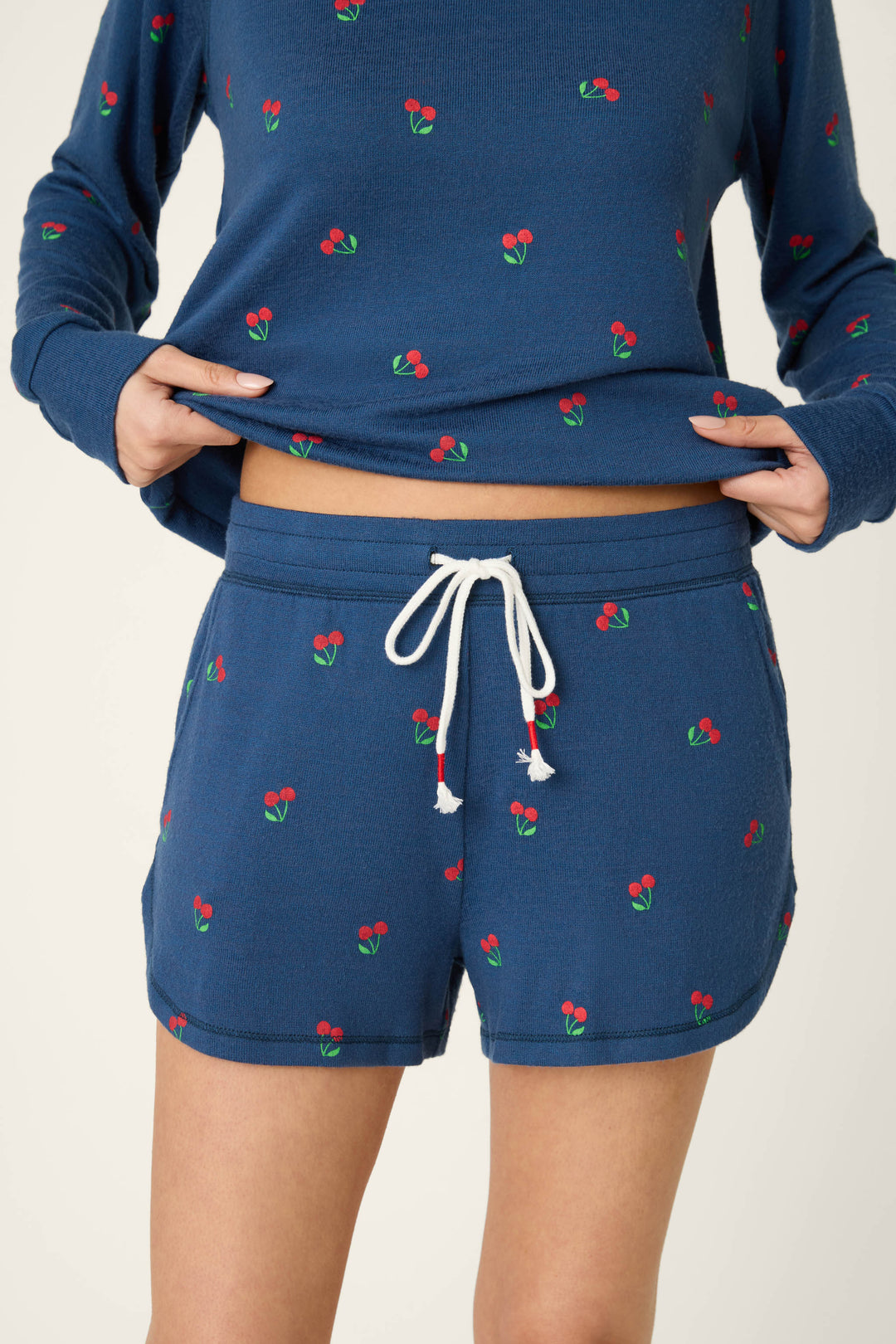 True navy blue fabric with a scattered red cherry print, soft texture, and white drawstring accent.