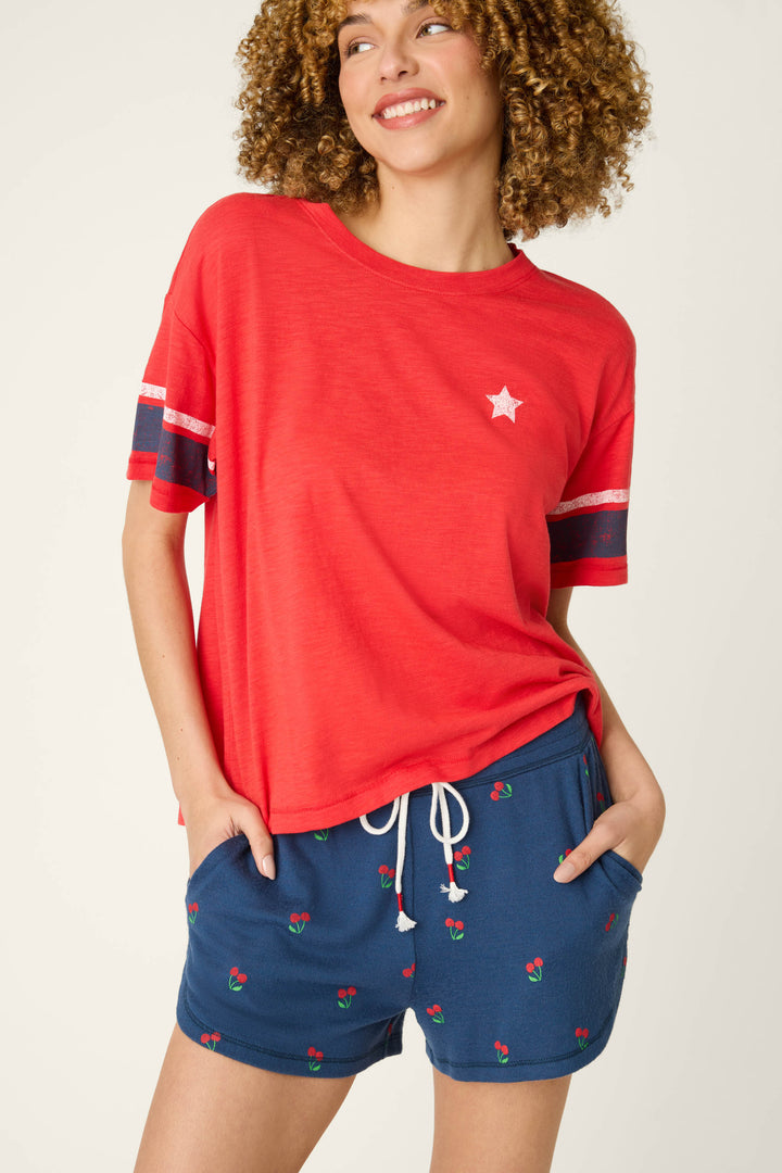 True scarlet fabric with a small white star alongside navy cloth printed with red and green cherries; smooth, lightweight texture.