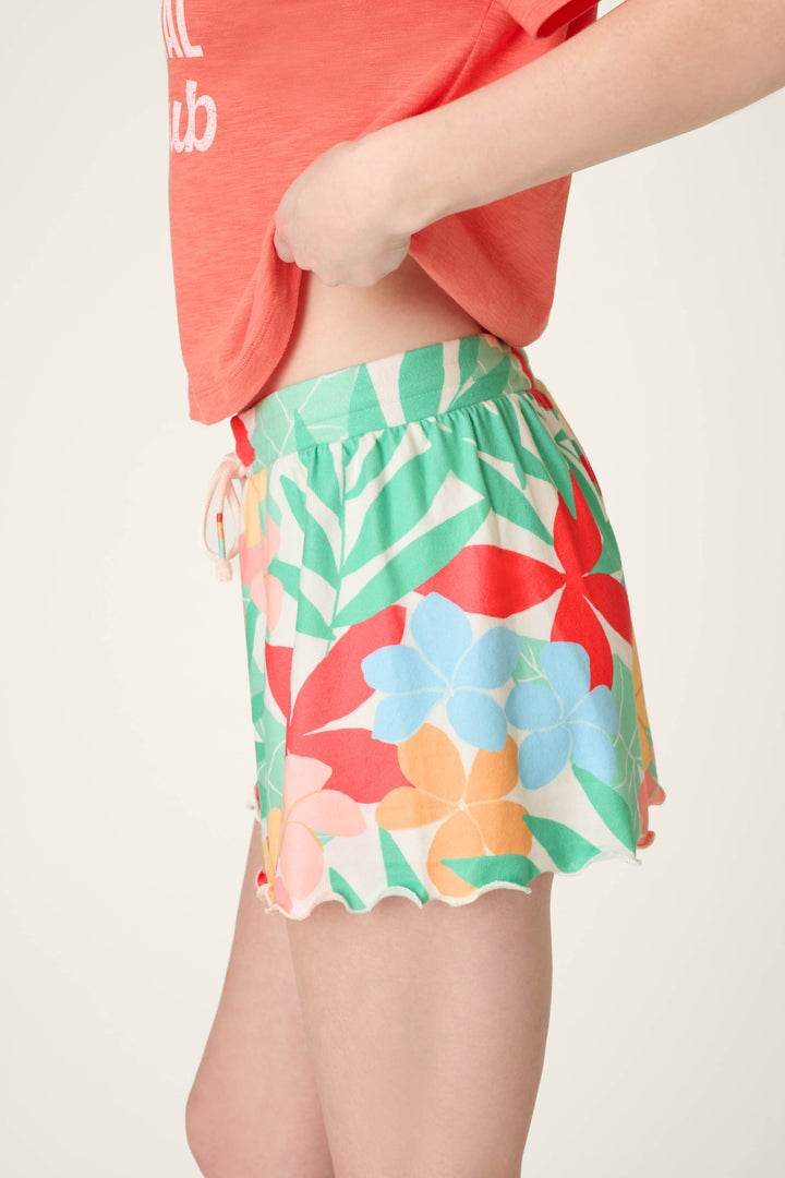Colorful floral print fabric with a ruffled edge, shown against a plain, light-colored background.