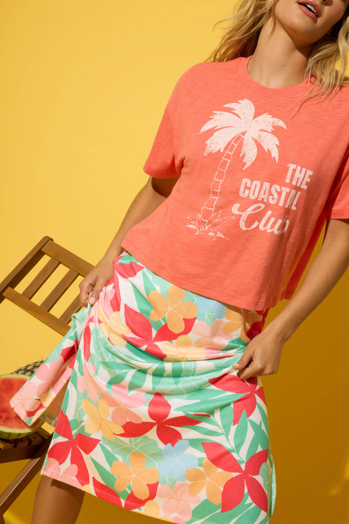 Coral fabric with a palm tree graphic print, combined with a colorful floral-patterned textile.
