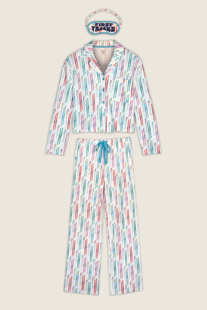 The Après All Day Ski Print 3-Piece PJ Set by P.J. Salvage includes a pajama set and matching sleep mask, featuring a white background with a colorful “Turn It Up” print in blue, red, and green. The pants are designed with a blue drawstring.