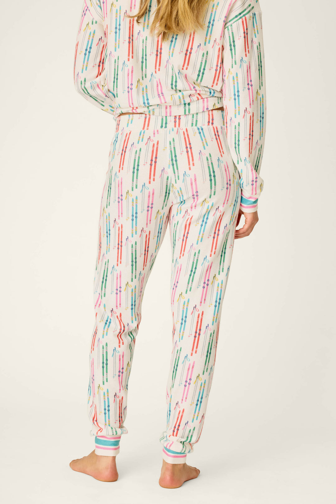 A person stands barefoot, facing away, wearing P.J. Salvage Après All Day Ski Print Jammie Pants. Only the lower half of their body is visible.