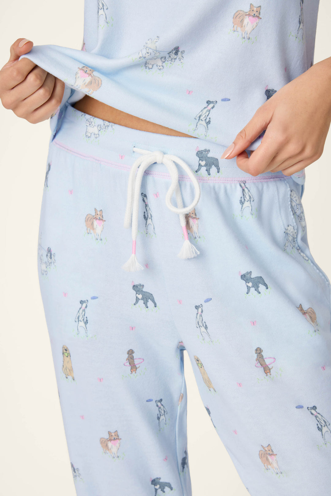 Model wears the P.J. Salvage Bark Park Fetch & Frolic Long PJ Set, featuring playful dog breeds on peachy-soft jersey fabric with jogger-style pants and a comfy waistband.