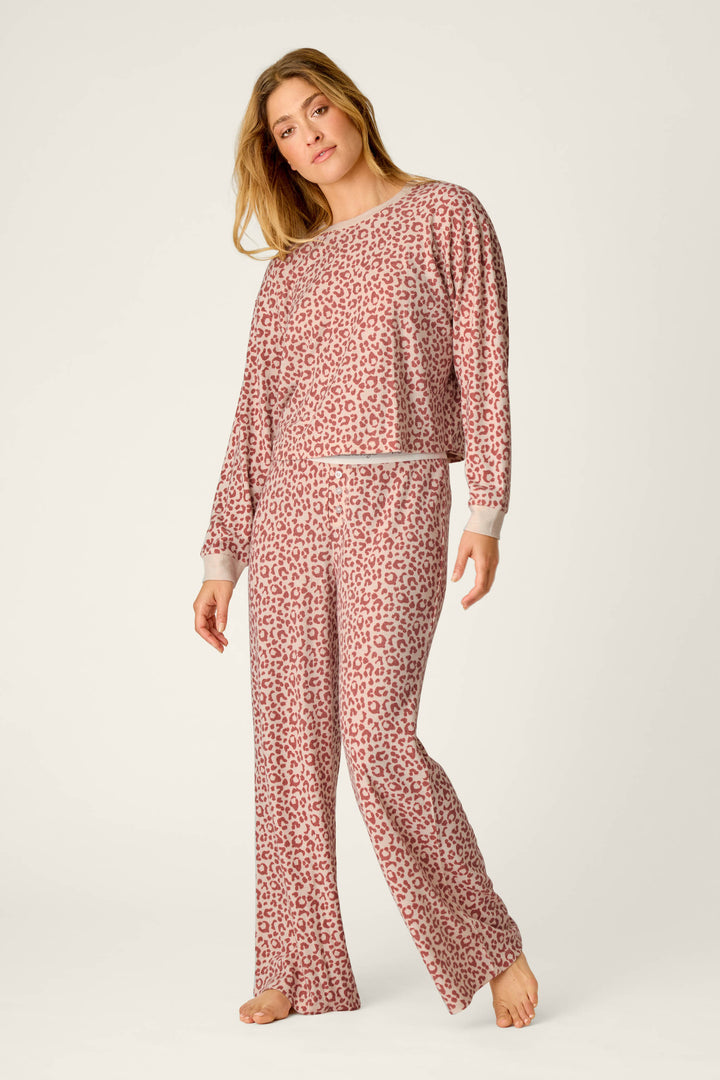 A woman stands barefoot against an off-white background wearing the P.J. Salvage Boyfriend Boxer Leopard Print Long Sleeve PJ Set.