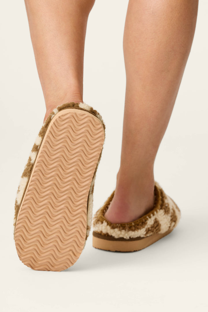 A person walks in P.J. Salvage Cheetah Bonita Dreams cheetah print fuzzy slippers with textured soles, shown from behind on a neutral background.