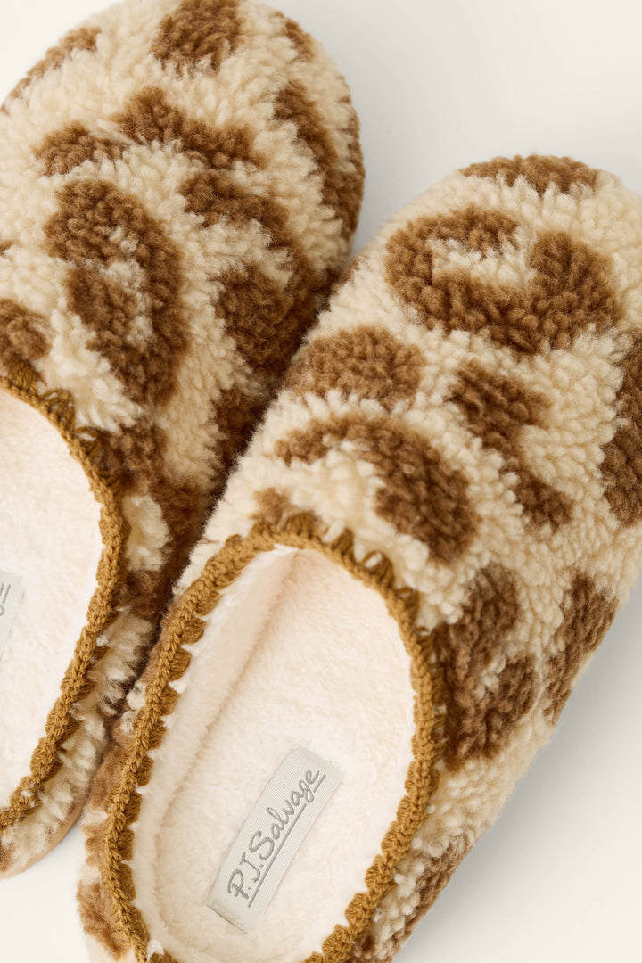 A pair of Cheetah Bonita Dreams Cheetah Print Fuzzy Slippers by P.J. Salvage, featuring a brown and cream cheetah print pattern. The slippers have light-colored insoles, a cozy textured look, and an inner label that reads P.J. Salvage.