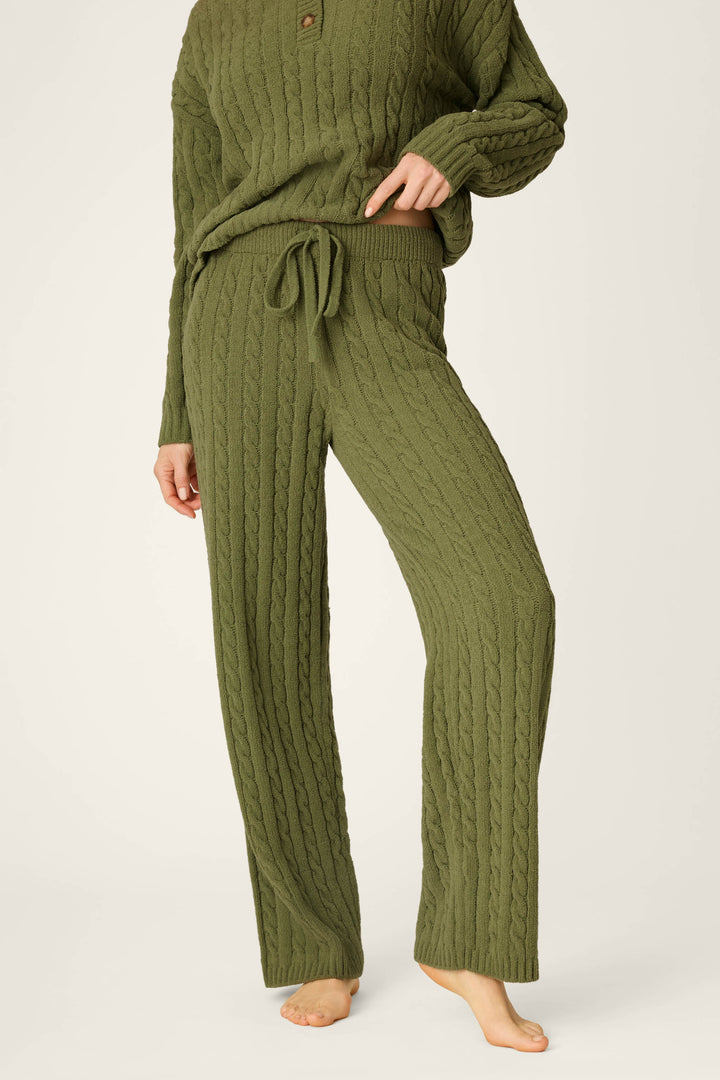 A person is shown barefoot from the waist down, wearing P.J. Salvage’s Cozy Chenille Cable Knit Olivine Lounge Pants against a light background.