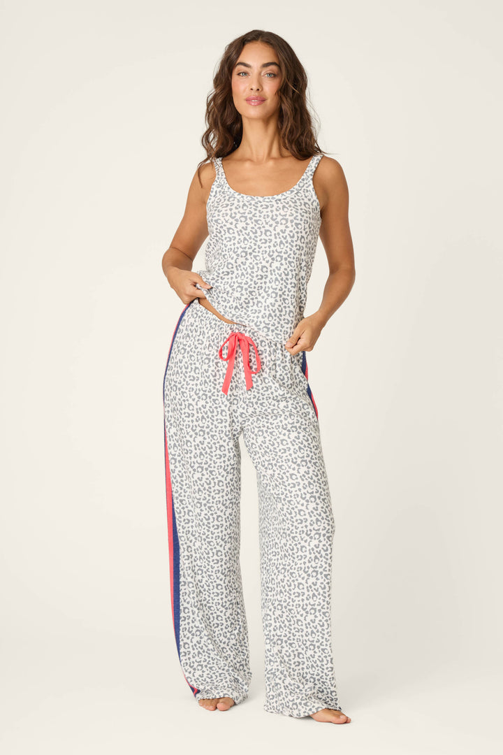 A woman stands barefoot in the P.J. Salvage Cat’s Meow Big Stretch Long PJ Set—leopard print wide-leg pants with a red drawstring and blue and red side stripes—facing forward with a relaxed expression.