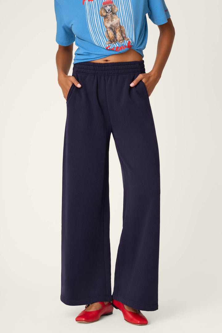 A person models the C'est La Vie Blue Ink BFF Lounge Pants by P.J. Salvage, paired with a blue dog graphic T-shirt and red shoes, standing with hands in pockets against a plain background.