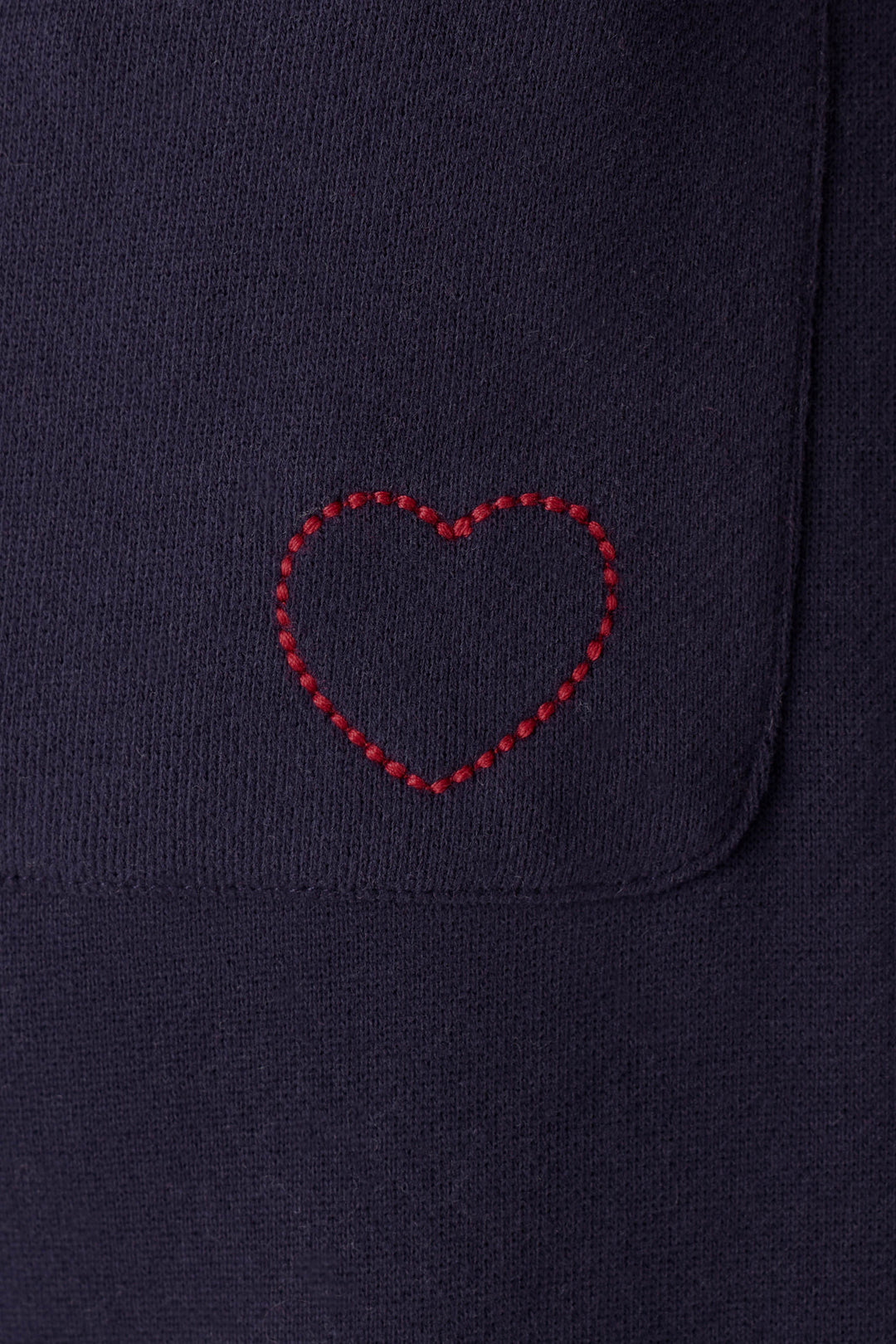 A red heart is stitched onto the C'est La Vie Blue Ink BFF Lounge Pants by P.J. Salvage, near the edge of a pocket on the dark navy blue fabric.