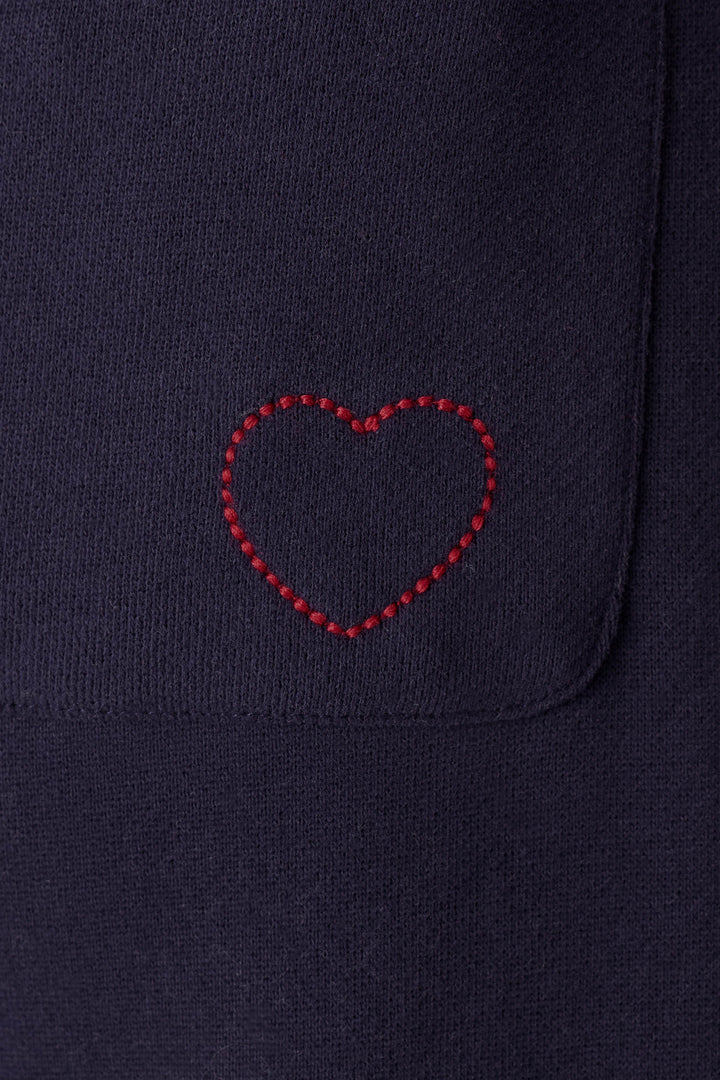 A red heart is stitched onto the C'est La Vie Blue Ink BFF Lounge Pants by P.J. Salvage, near the edge of a pocket on the dark navy blue fabric.