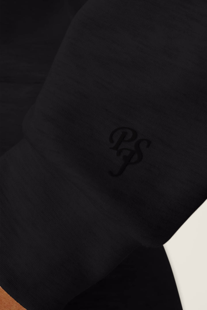 A close-up of the C'est La Vie Midnight Flights Overnight Sweater by P.J. Salvage, featuring the letters PSJ subtly embroidered in black thread on black fabric.