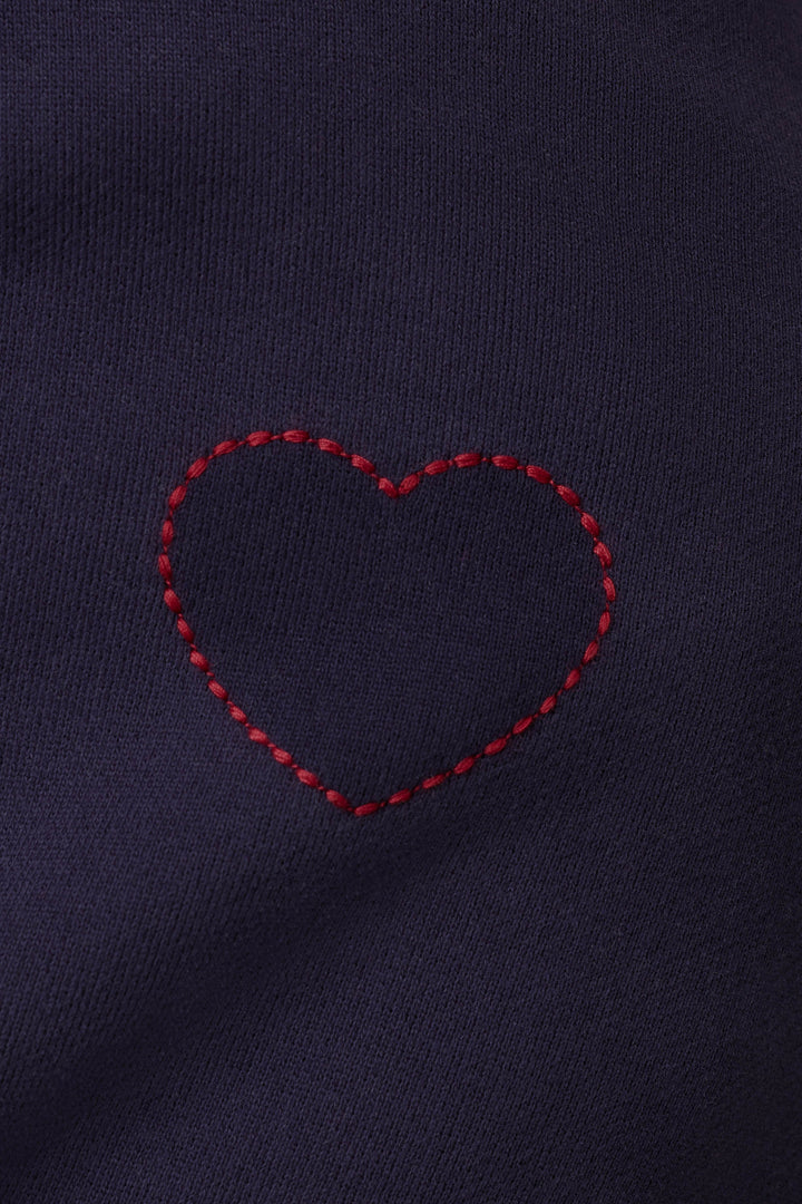 A blue ink “Simone” sweater by P.J. Salvage featuring a red stitched heart outline on dark purple fabric.
