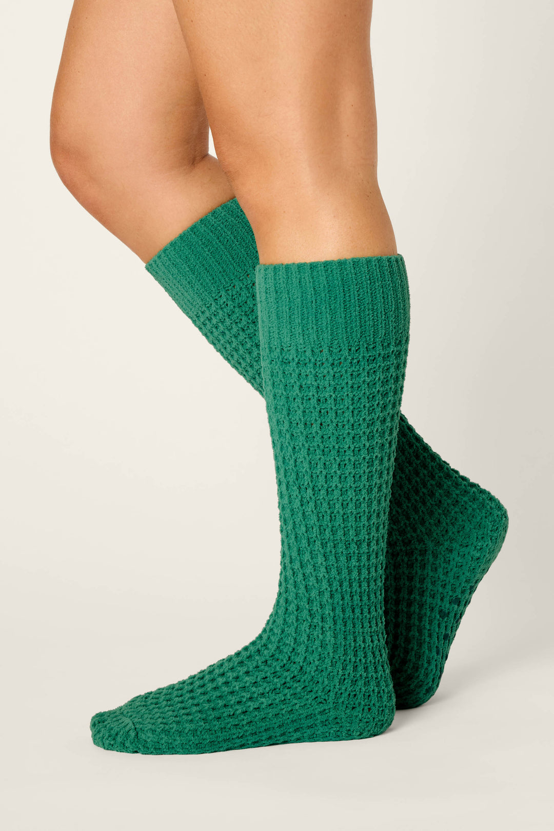 A person wearing P.J. Salvage Cozy Chenille Waffle Green Mid-Calf Socks stands with one foot slightly in front of the other against a plain background.