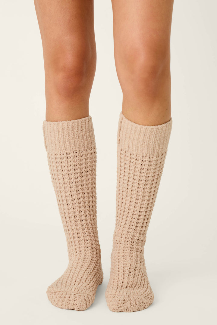 A person wearing P.J. Salvage Cozy Chenille Waffle Smoky Beige Mid-Calf Socks stands on a light background with their feet close together.