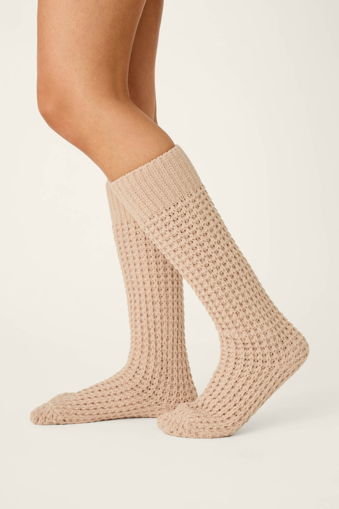 A person wearing P.J. Salvage Cozy Chenille Waffle Smoky Beige Mid-Calf Socks stands on a neutral background, displaying a side view of their lower legs and feet.