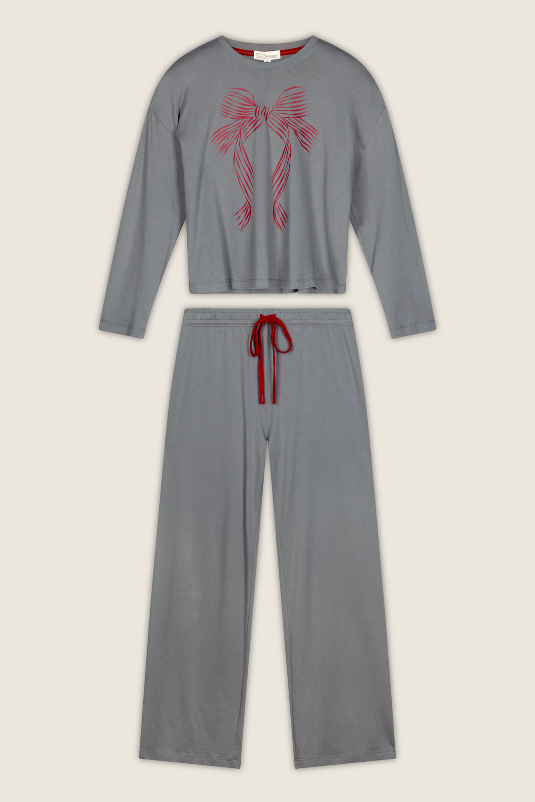 The Bow Graphic Long Sleeve Pajama Set by P.J. Salvage is laid flat on a light background, showcasing its gray design with long sleeves and wide-leg pants. The top features a pink bow graphic, while the waistband is accented with a red drawstring.