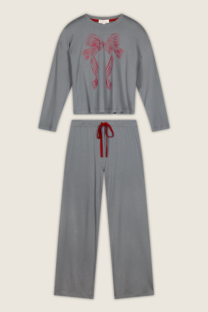 The Bow Graphic Long Sleeve Pajama Set by P.J. Salvage is laid flat on a light background, showcasing its gray design with long sleeves and wide-leg pants. The top features a pink bow graphic, while the waistband is accented with a red drawstring.