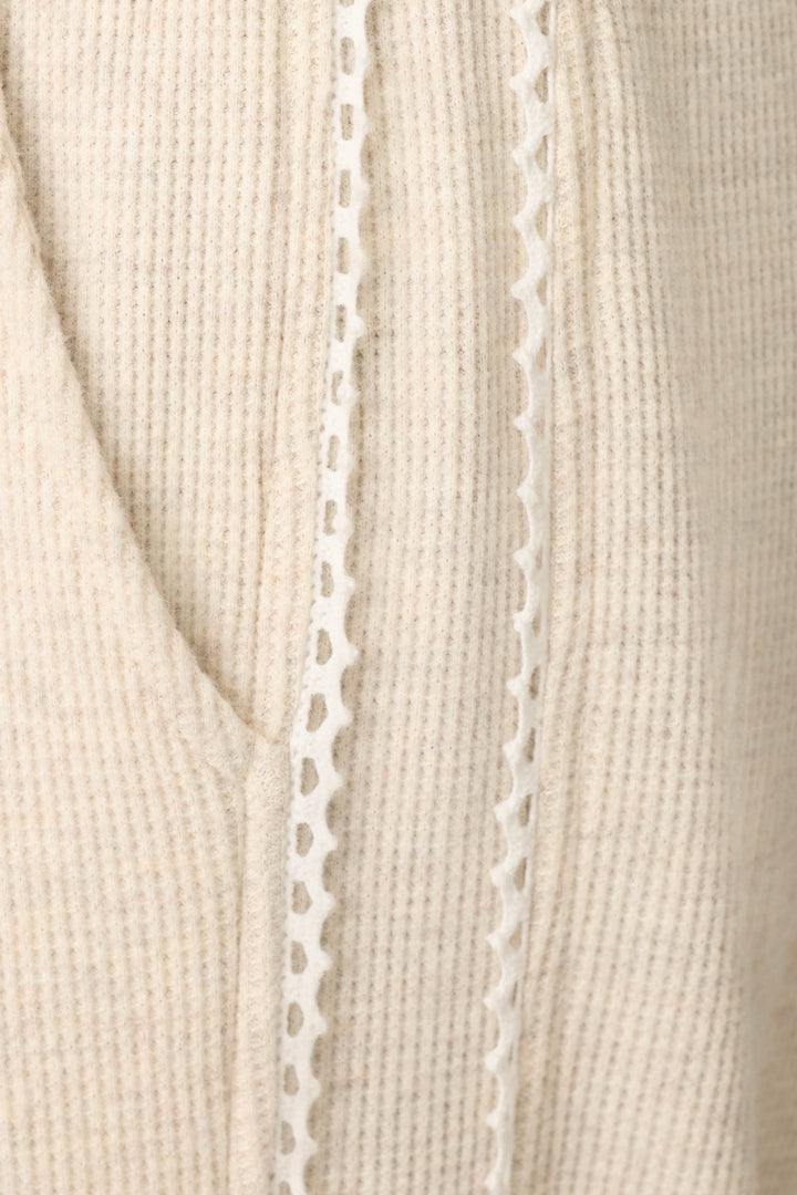 Close-up of the Weekday Waffles Oatmeal Lounge Pants by P.J. Salvage, featuring beige ribbed fabric with a decorative white lace trim running vertically alongside a seam or pocket.