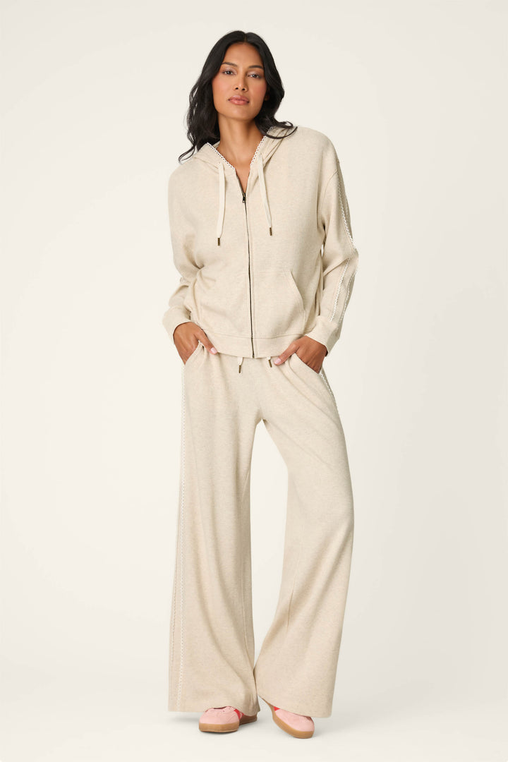 A woman stands facing forward against a plain light background, hands in her pockets, wearing the P.J. Salvage Weekday Waffles Oatmeal Lounge Pants with a matching beige zip-up hoodie and light pink shoes.