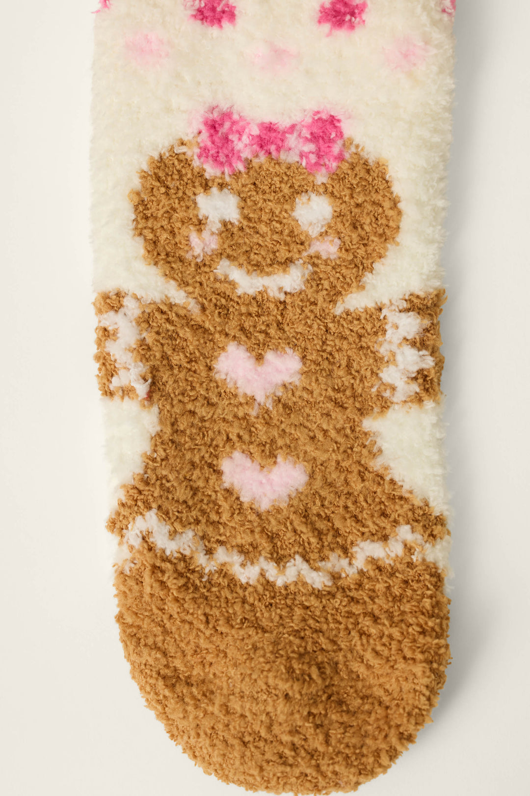 The P.J. Salvage Gingerbread Girl & Polka Dots Socks are fuzzy white socks adorned with a brown gingerbread girl design, pink hearts, a pink bow, and pink polka dots at the top.