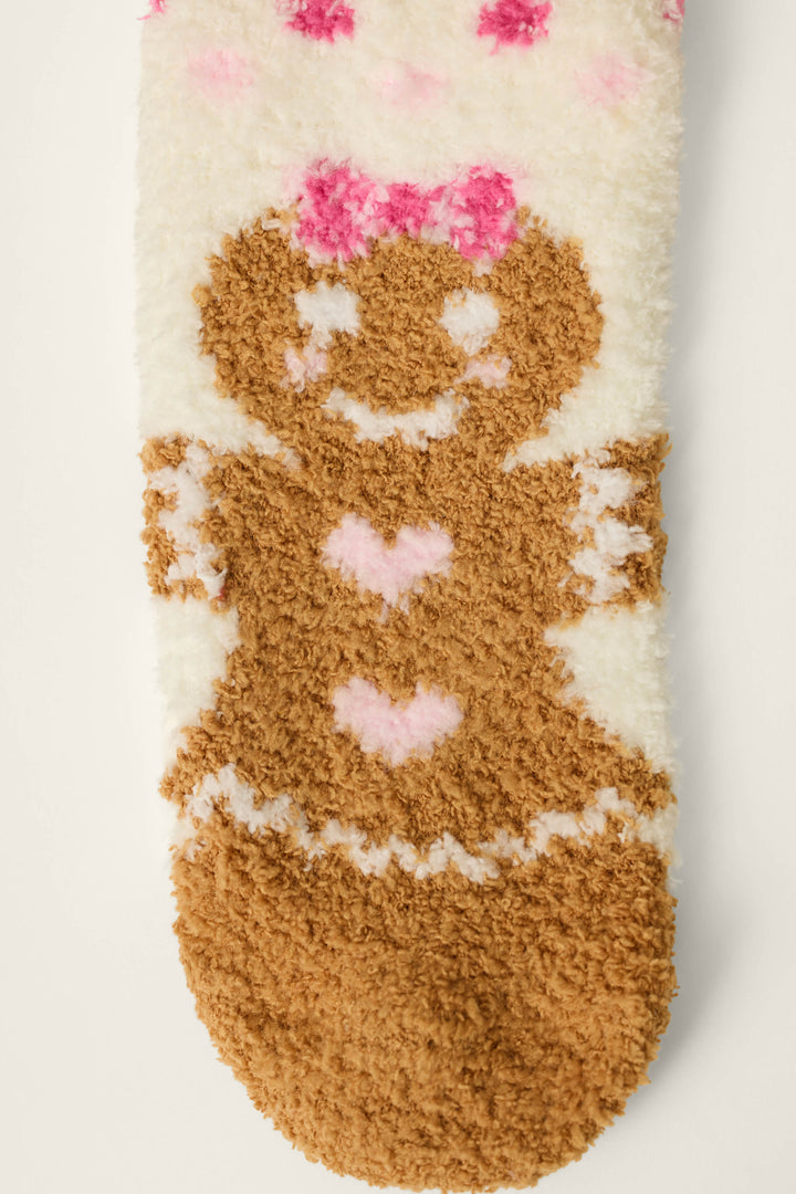 The P.J. Salvage Gingerbread Girl & Polka Dots Socks are fuzzy white socks adorned with a brown gingerbread girl design, pink hearts, a pink bow, and pink polka dots at the top.