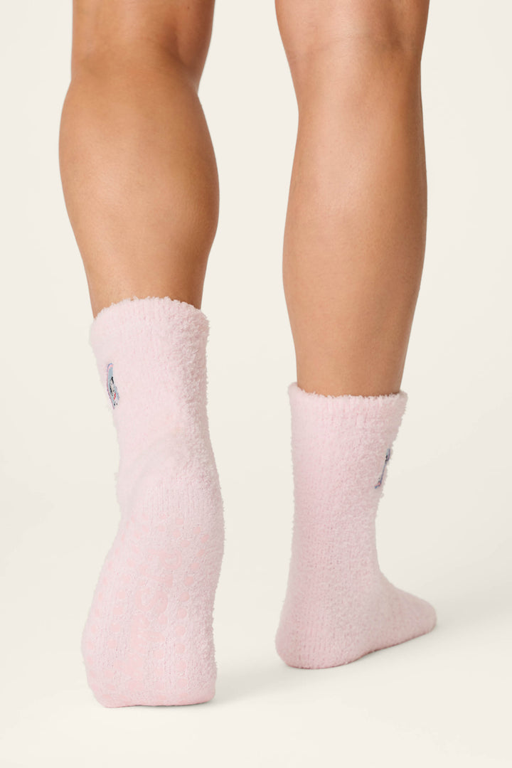 Two legs wearing P.J. Salvage’s Puppy Portrait Socks—soft, fuzzy light pink socks with a cozy texture—are pictured from the back on a plain light background. The socks reach just above the ankles.