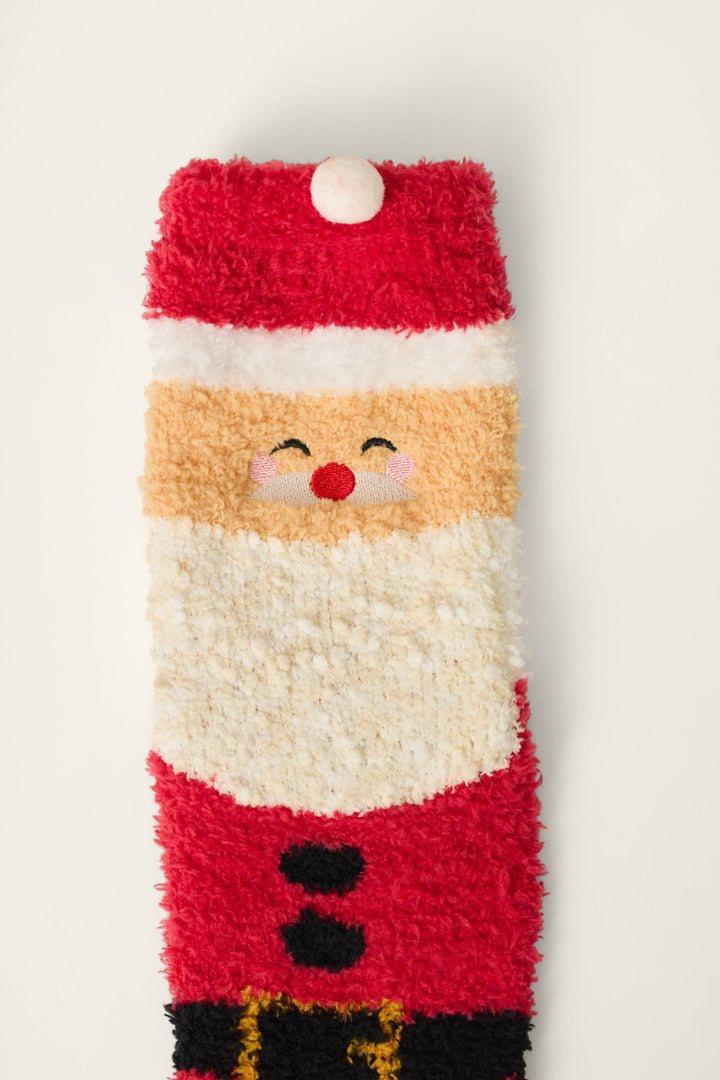 The Jolly Santa Claus Socks by P.J. Salvage are fuzzy socks featuring a cheerful Santa Claus with a red hat, white beard, rosy cheeks, and a smiling face, set against a plain white background.