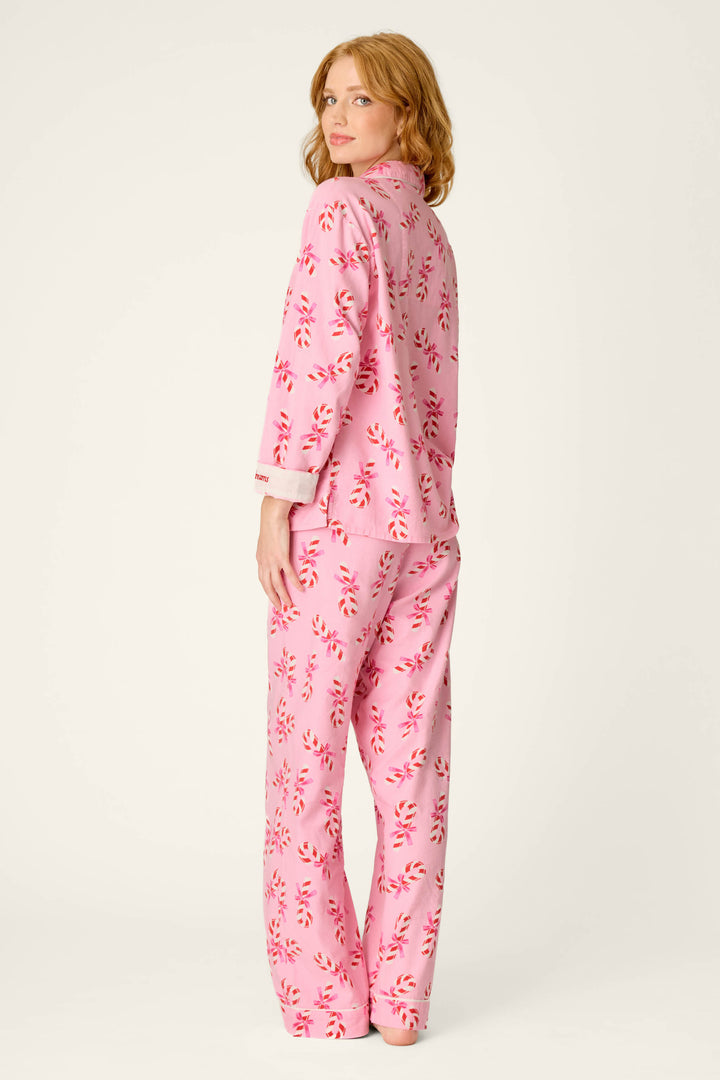 A woman with wavy red hair, dressed in the P.J. Salvage Sweeter Than Sugar Candy Cane Print 4-Piece PJ Set, stands and looks over her shoulder against a plain light background.