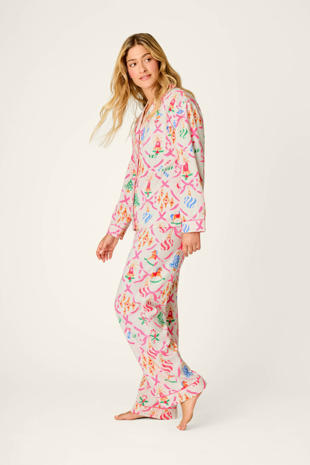 Wearing the Deck the Halls Ornament Print 4-Piece PJ Set by P.J. Salvage, a person stands barefoot against a light background, looking to the side while walking.