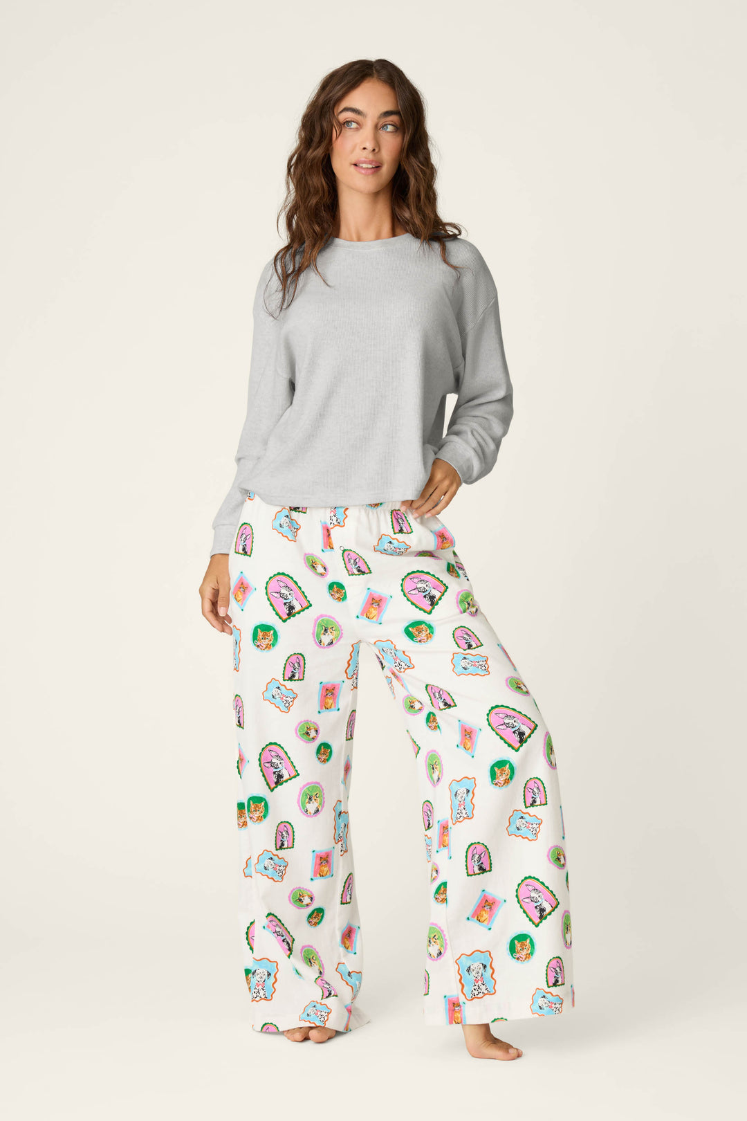 A woman wearing the P.J. Salvage Heather Grey Long Sleeve Top and white pajama pants with colorful taco and cactus prints stands barefoot against a plain light background.