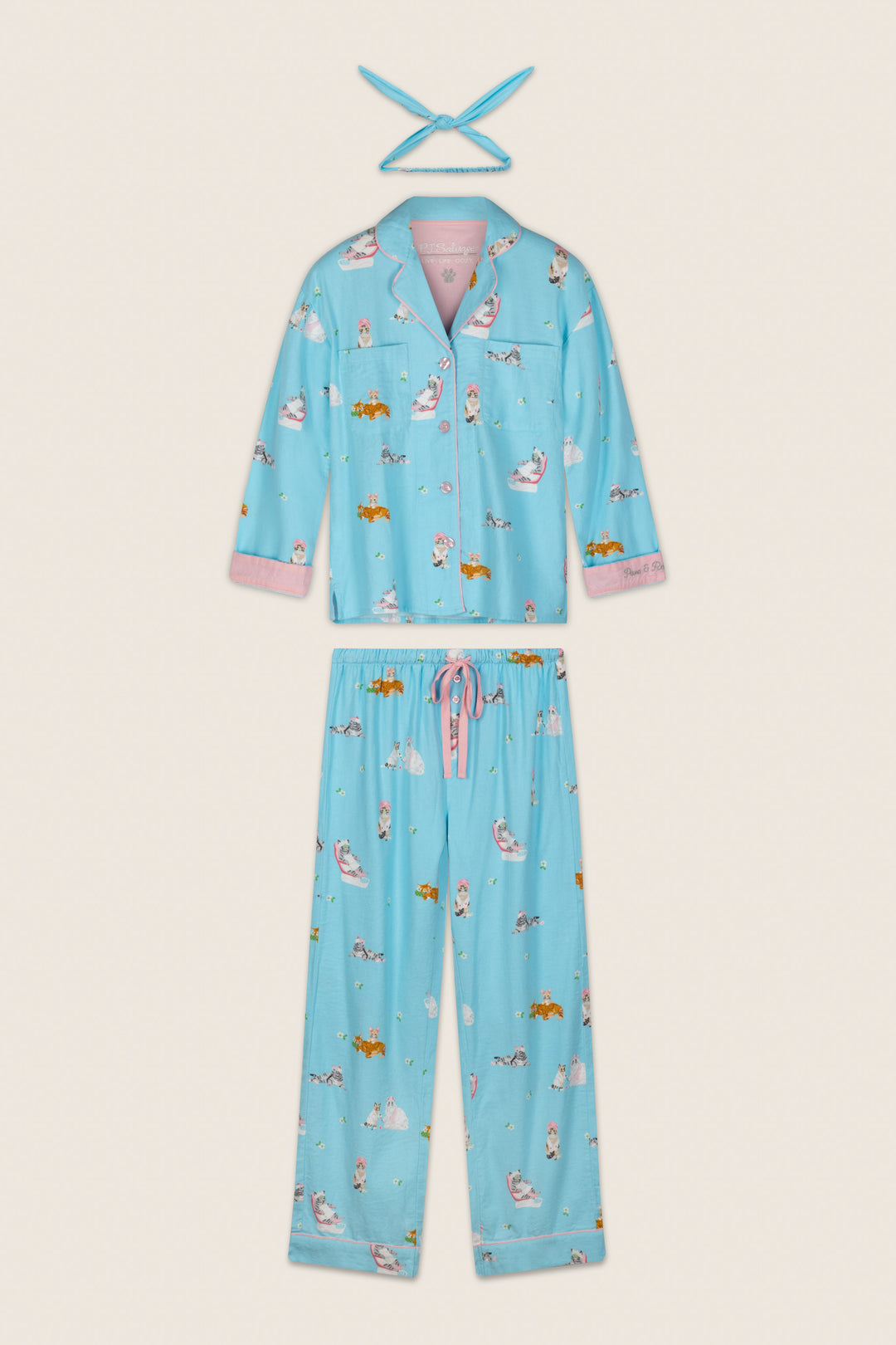 Slip into the cozy P.J. Salvage Pampered Cat Print 3-Piece Long Sleeve Flannel PJ Set, featuring a light blue pajama top and pants adorned with playful cat prints, pink trim on the cuffs, and a matching pink and blue tie headband.