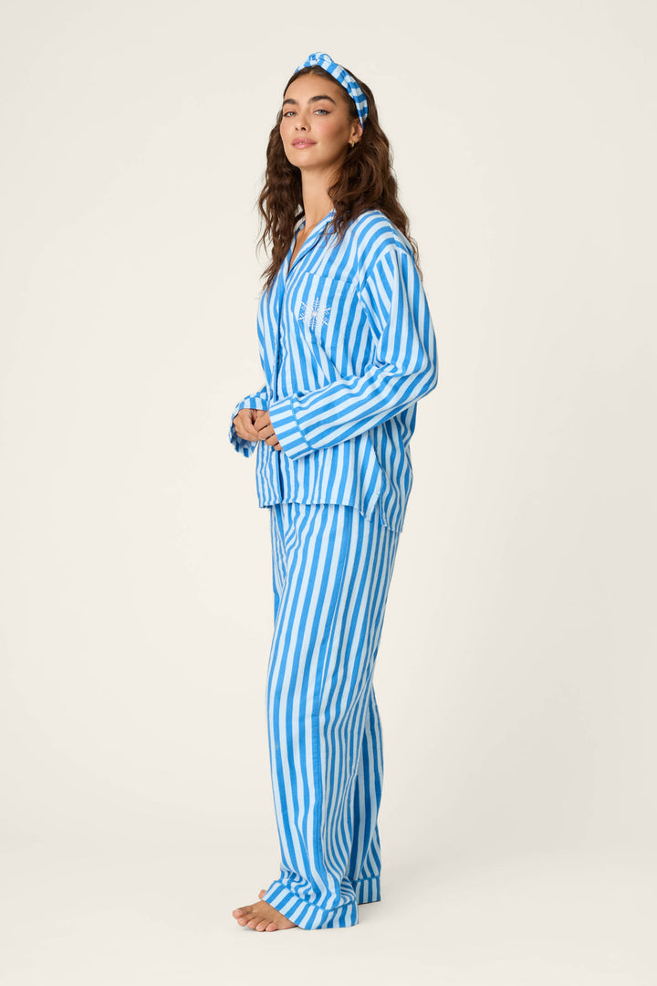 A woman stands in profile against a neutral background, wearing the P.J. Salvage Snowflake Icon 3-Piece Long Sleeve Flannel PJ Set in blue and white stripes with a matching headband, her hands clasped in front of her.