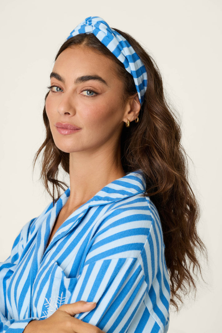 A woman with long wavy brown hair, looking at the camera with her arms crossed against a plain light background, wears the Snowflake Icon 3-Piece Long Sleeve Flannel PJ Set by P.J. Salvage.