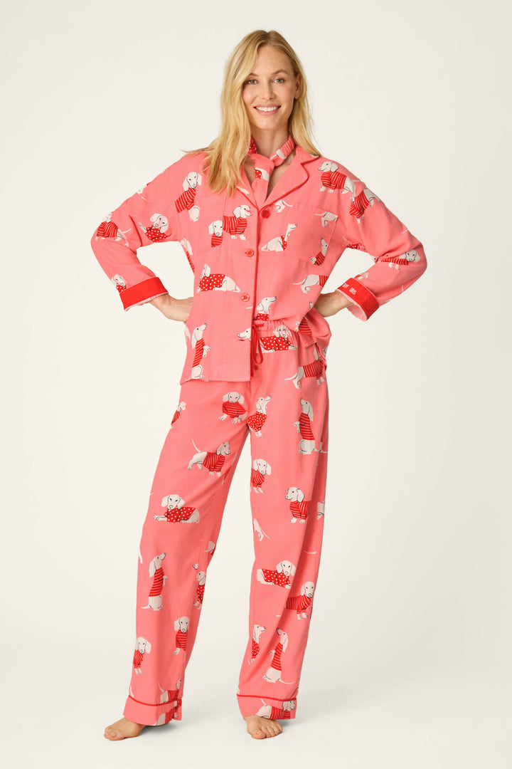 A smiling woman stands barefoot with her hands on her hips, modeling the P.J. Salvage Dachshund Print 3-Piece Flannel PJ Set against a plain light background.