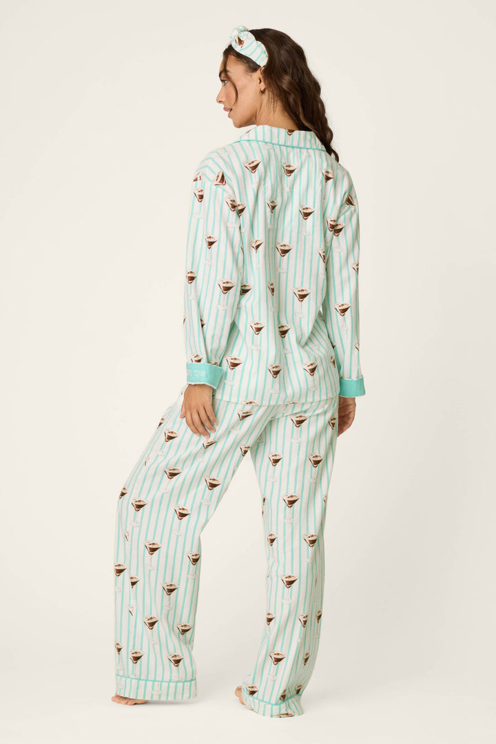 A woman stands barefoot with her back to the camera, wearing the P.J. Salvage Espresso Martini Print 3-Piece Long Sleeve Flannel PJ Set and a matching headband, both featuring an espresso martini pattern.