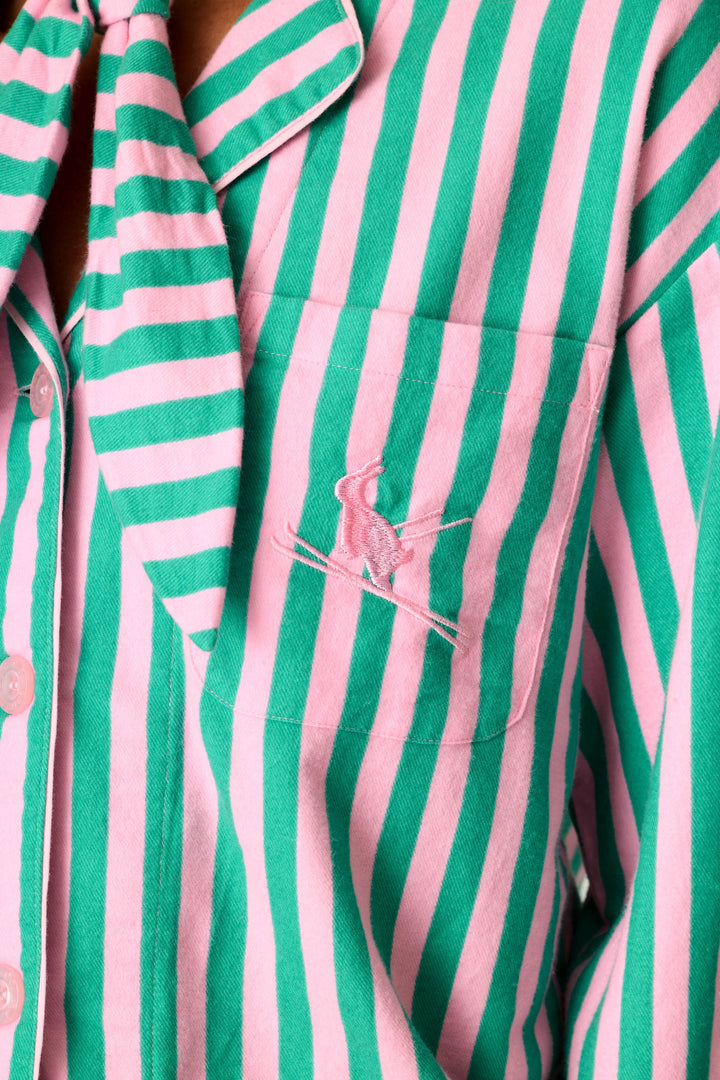 Close-up of the P.J. Salvage Ski Bunny Icon 3-Piece Long Sleeve Flannel PJ Set, showcasing its pink and green vertical stripes and a pocket embroidered with the iconic crossed polo mallets and figure logo.