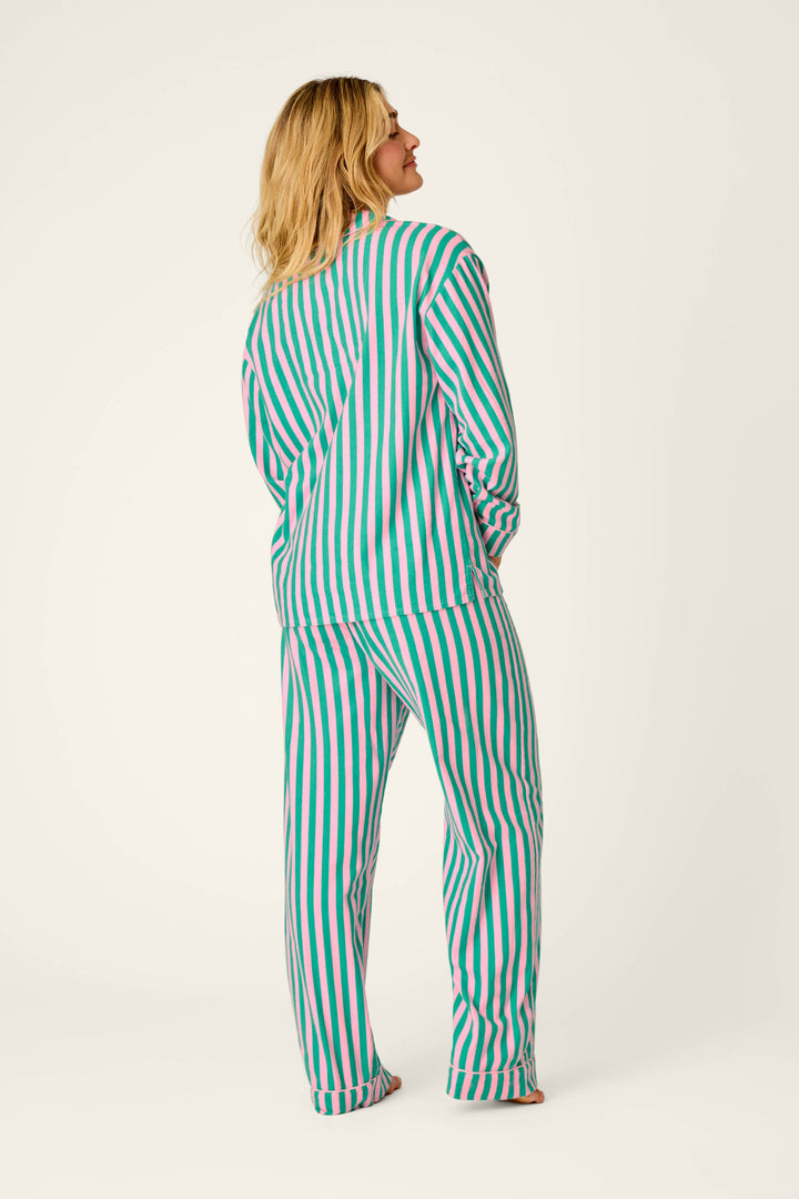 A person stands facing away against a plain light background, wearing the P.J. Salvage Ski Bunny Icon 3-Piece Long Sleeve Flannel PJ Set, which features matching vertical green, pink, and white stripes.