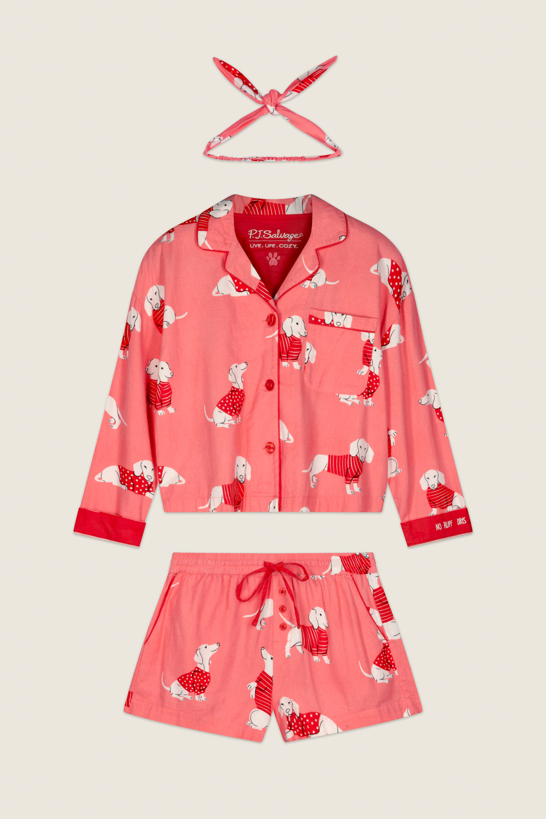 The P.J. Salvage Dachshund Print 3-Piece Short Flannel PJ Set, featuring a pink long-sleeve button-up top, drawstring shorts, and a matching headband, is displayed flat on a light background.