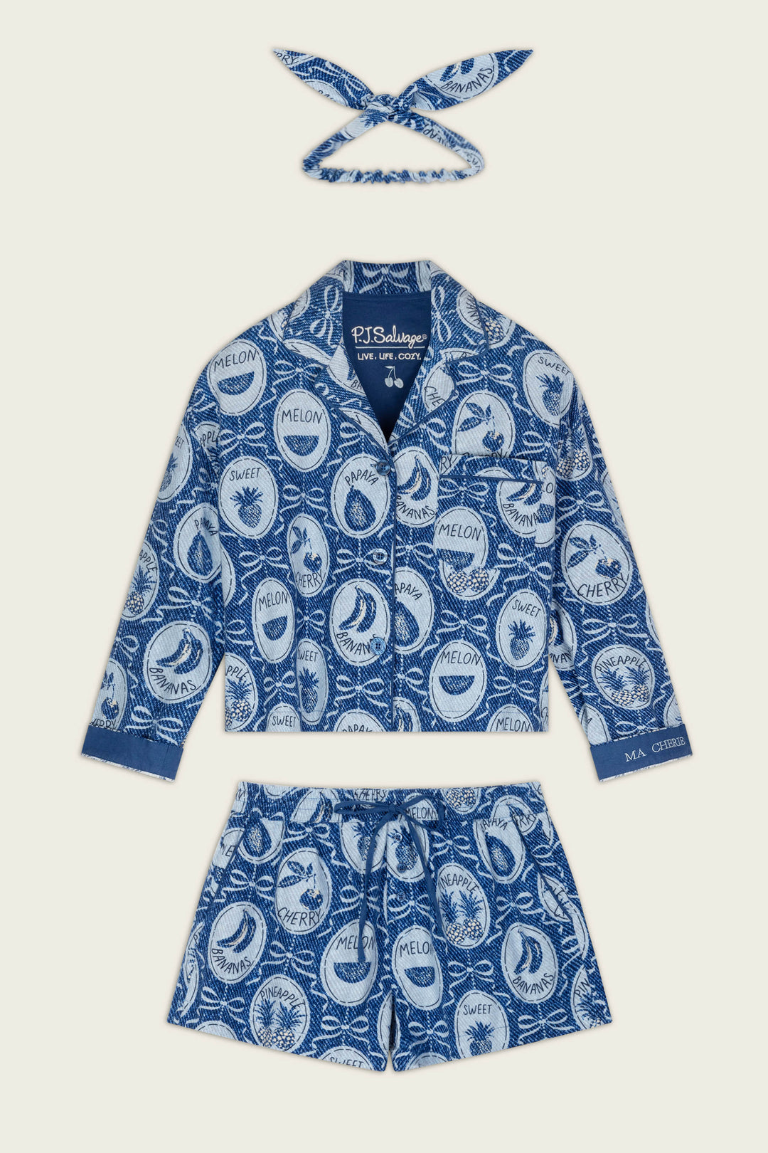 The Fruit Medley Print 3-Piece Short Flannel PJ Set by P.J. Salvage features a blue and white pajama set adorned with playful circular fruit labels and names like melon, banana, and cherimoya. This set includes a collared button-up shirt, drawstring shorts, and a matching headband.