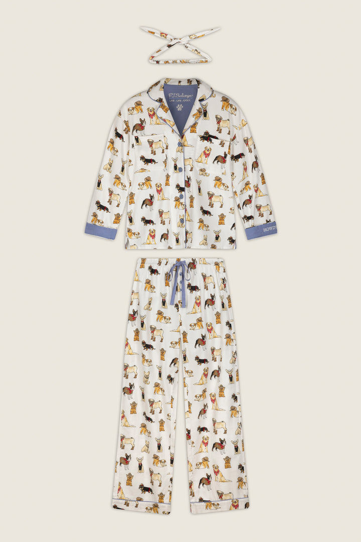 The Howdy Pup-ner Dog Print 3-Piece Flannel PJ Set by P.J. Salvage features a white pajama set with playful, colorful dog illustrations. This set includes a matching headband, a top with blue accents on the collar and cuffs, and full-length relaxed fit pants.