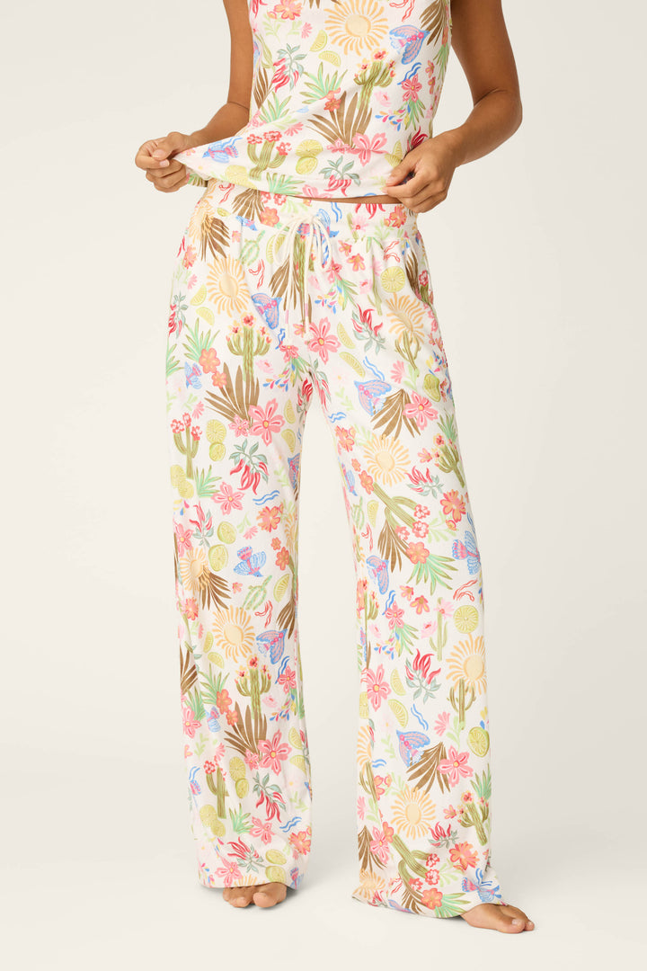 A person stands barefoot against a plain, light background, showing off the colorful print of the Feelin' Prickly Desert Dreams Pajama Pants by P.J. Salvage—perfect for cozy nights.