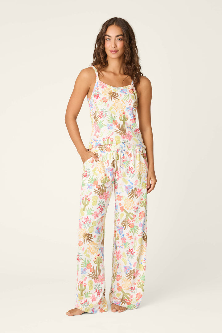 A woman stands barefoot in P.J. Salvage's Feelin' Prickly Desert Dreams Pajama Pants, featuring a colorful floral and cactus print, her hand in one pocket and a gentle smile on her face, ready for cozy nights.