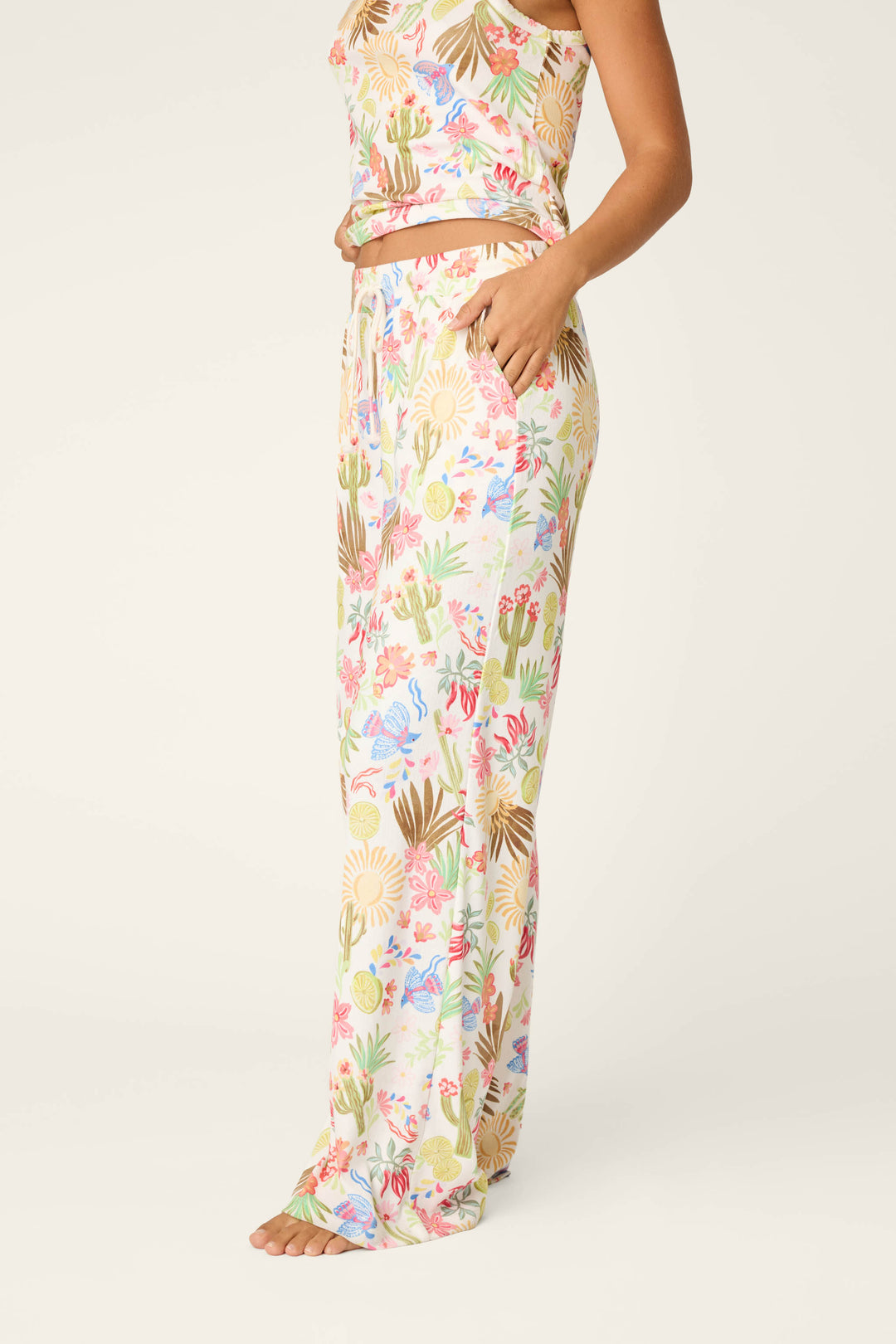 A woman stands barefoot in P.J. Salvage Feelin' Prickly Desert Dreams Pajama Pants—relaxed fit, wide-leg pants with a colorful floral and cactus print—perfect for cozy nights, set against a plain light background.