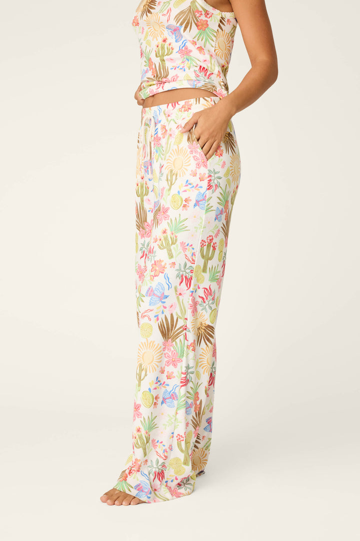A woman stands barefoot in P.J. Salvage Feelin' Prickly Desert Dreams Pajama Pants—relaxed fit, wide-leg pants with a colorful floral and cactus print—perfect for cozy nights, set against a plain light background.