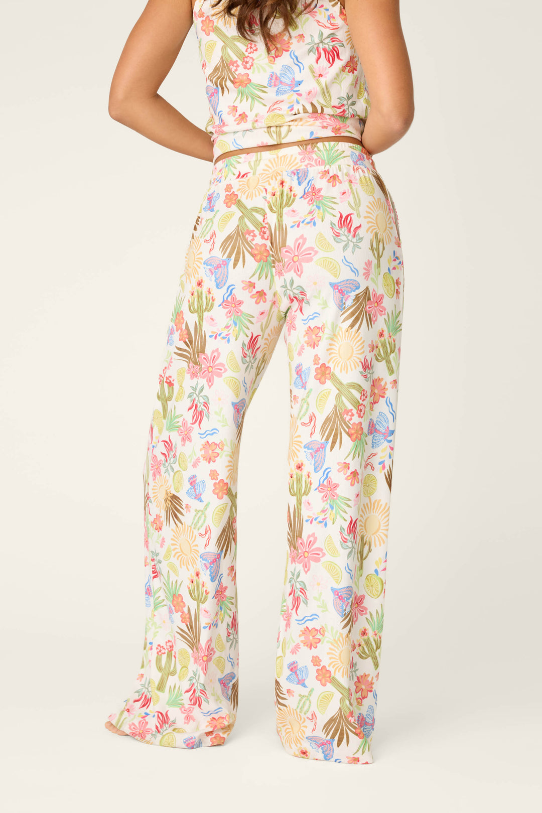 A person stands with their back to the camera, showcasing the Feelin' Prickly Desert Dreams Pajama Pants by P.J. Salvage—high-waisted, wide-leg, and perfectly comfy for cozy nights. The background is light and plain.