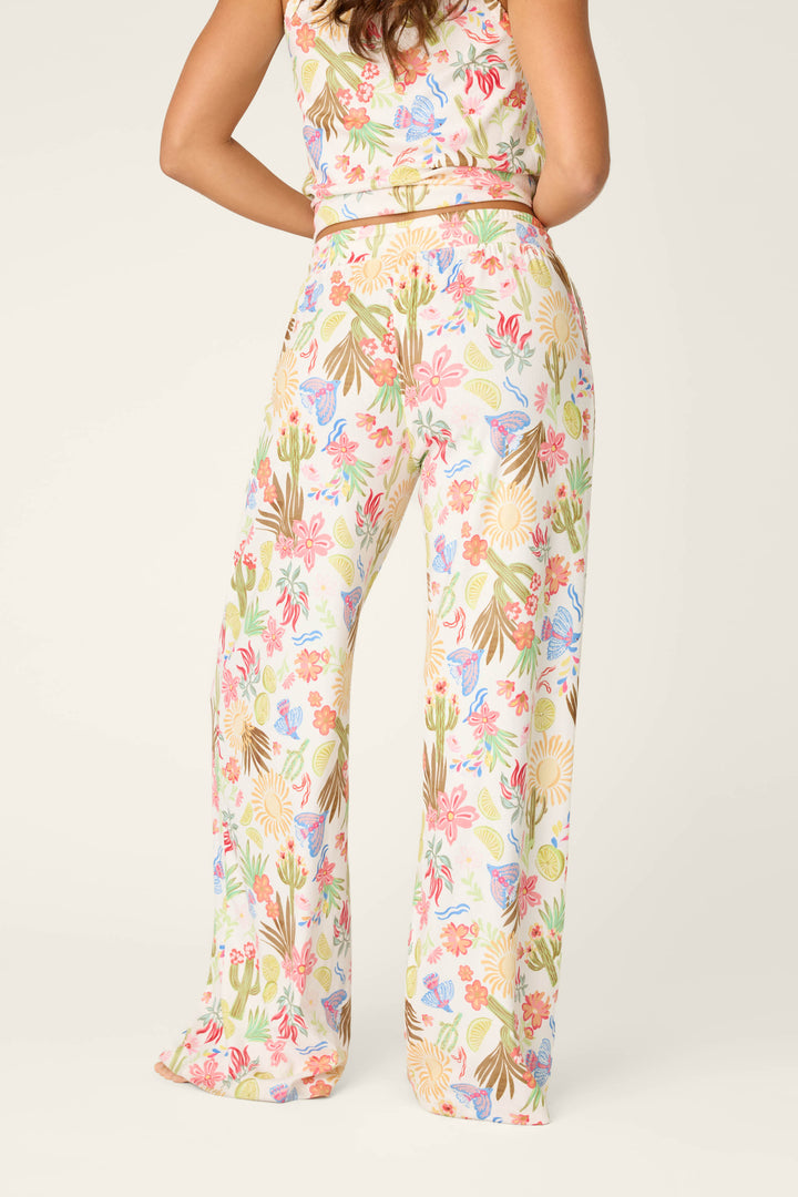 A person stands with their back to the camera, showcasing the Feelin' Prickly Desert Dreams Pajama Pants by P.J. Salvage—high-waisted, wide-leg, and perfectly comfy for cozy nights. The background is light and plain.