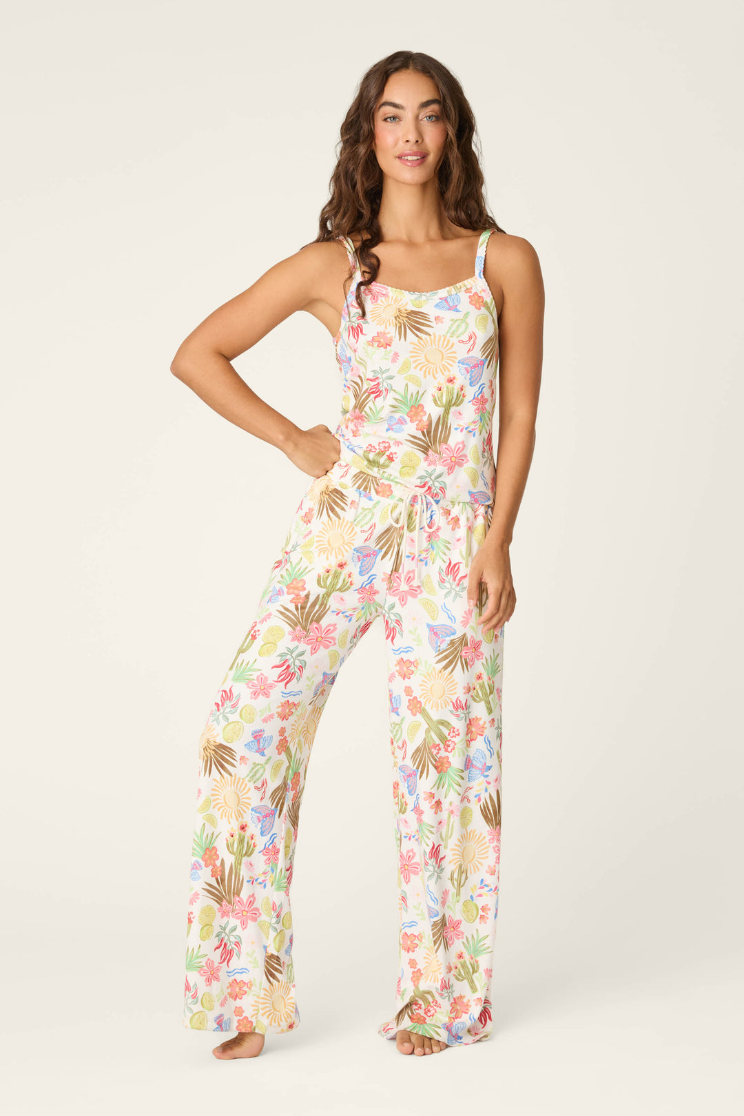 A woman with long, wavy brown hair stands barefoot against a light background, wearing the P.J. Salvage Feelin' Prickly Desert Dreams Camisole featuring a colorful desert-inspired print.