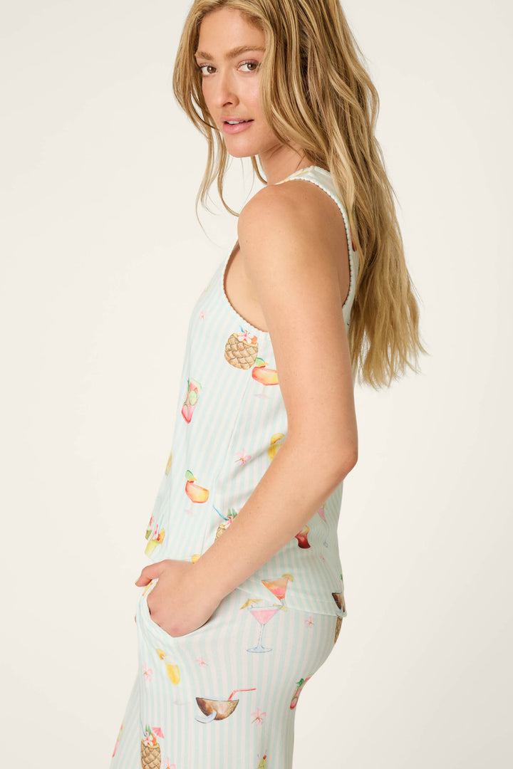 A woman with long blonde hair models the P.J. Salvage It's Five O'clock Somewhere Cocktail Print Tank Top, standing in profile with one hand in her pocket and looking over her shoulder.