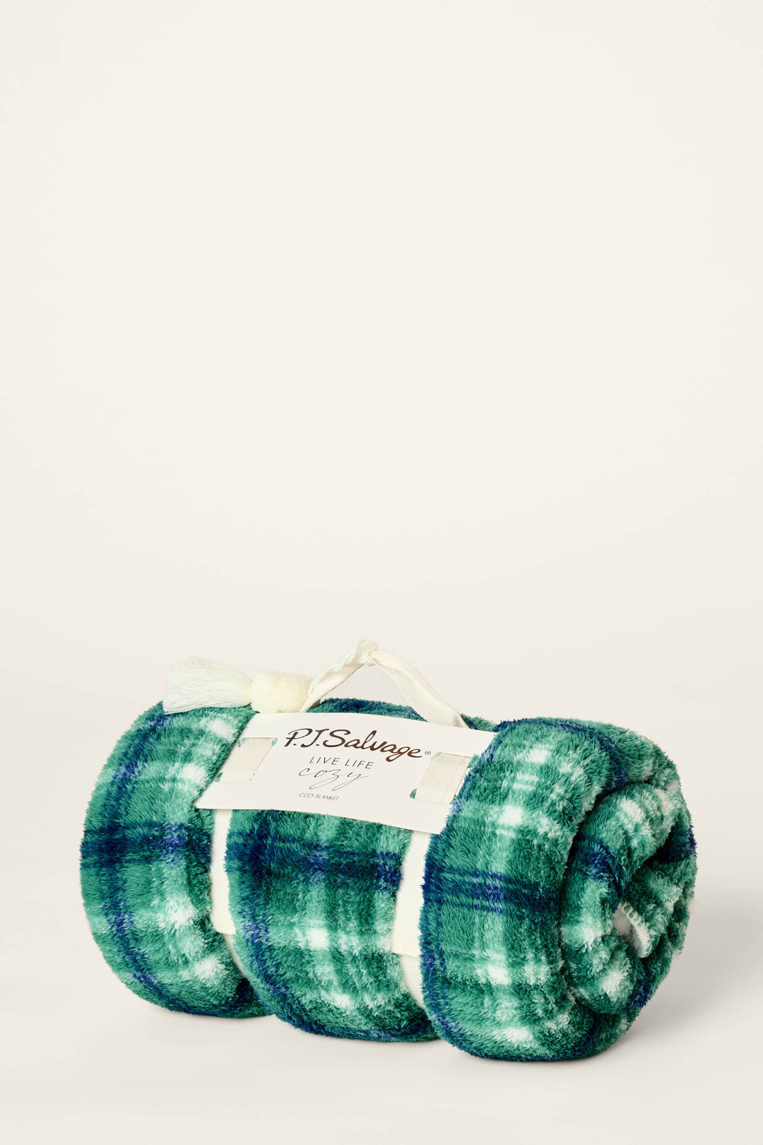 A green and blue plaid Let’s Get Cozy Plaid Throw Blanket by P.J. Salvage, rolled up and tied with a white ribbon, featuring a label with the brand name on the front.
